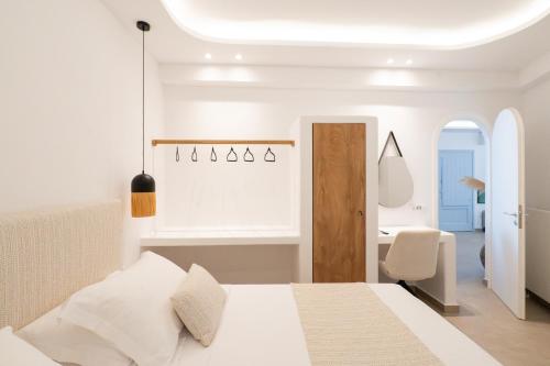 a white bedroom with a bed and a desk at SN Santorini Apartments in Kamari