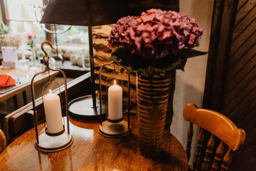 a table with two candles and a vase with flowers at Auberge Aal Veinen in Vianden