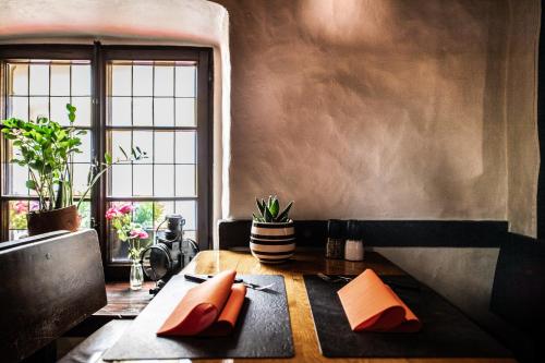 a table with orange napkins on it in a room with a window at Auberge Aal Veinen in Vianden