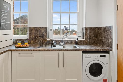 a kitchen with a sink and a washing machine at Spacious 2 Bed Apartment With Secure Free Parking in Liverpool