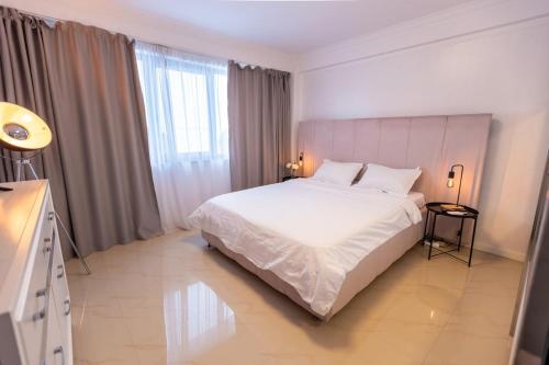 a bedroom with a white bed and a large window at White Residence Steaua De Mare in Eforie Nord