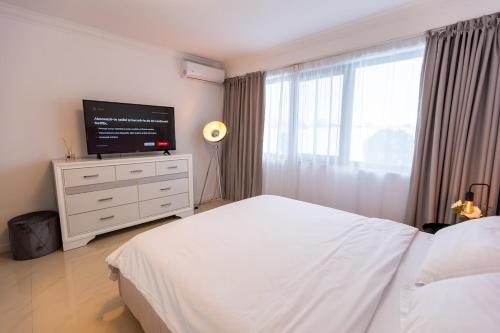 a bedroom with a bed and a flat screen tv at White Residence Steaua De Mare in Eforie Nord