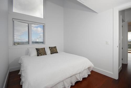 a white bedroom with a bed with two pillows on it at Wharau Lodge in Kerikeri