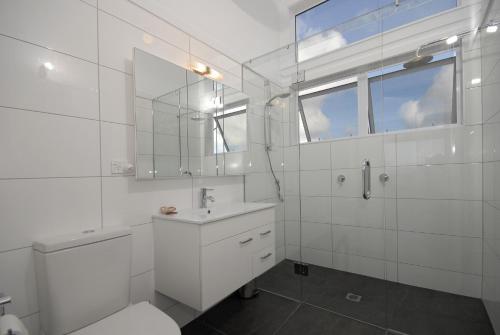 a white bathroom with a sink and a mirror at Wharau Lodge in Kerikeri