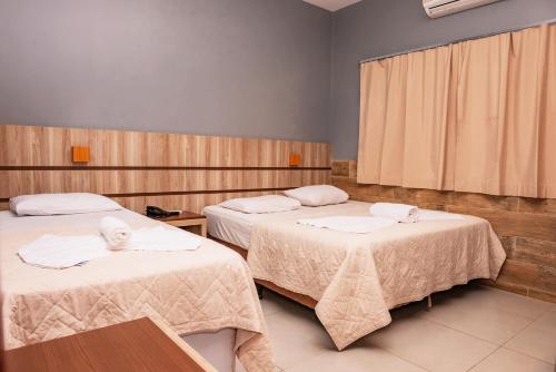 a hotel room with two beds with white sheets at Hotel Nacional in Jataí