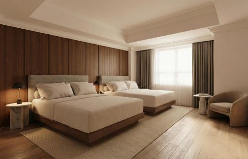 a bedroom with two beds and a chair and a window at Metcalfe Hotel Montréal by Gray Collection in Montreal
