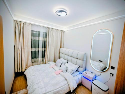 a bedroom with a bed and a large mirror at Skyline Luxury 17th-Floor 1BR near Junction Mall - City Views, Pool, Gym & Full-Body Massage Chair in Nairobi