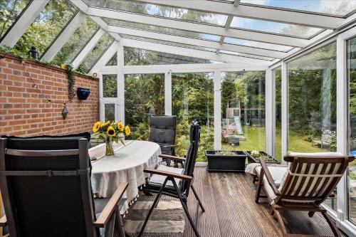 a glass conservatory with a table and chairs at Cozy House Close to Beach and B&O in Struer