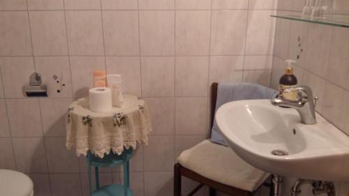 ein Badezimmer mit einem Waschbecken, einem WC und einem Stuhl in der Unterkunft Darja Guesthouse in Dob