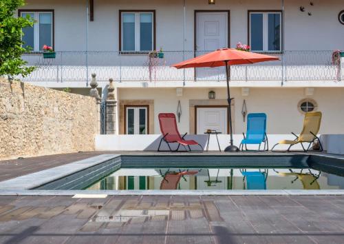 two chairs and an umbrella sitting next to a pool at Casa de Tent'tugal in Tentúgal
