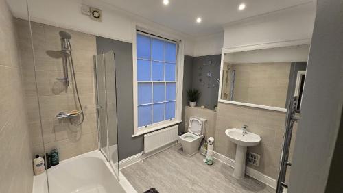 a bathroom with a shower toilet and a sink at Seaside 4 bed terraced house in Hastings