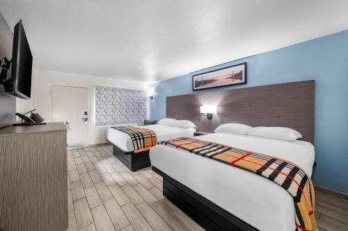 ein Hotelzimmer mit zwei Betten und einem Flachbildfernseher in der Unterkunft Rodeway Inn Lake Wales - Winter Haven in Lake Wales