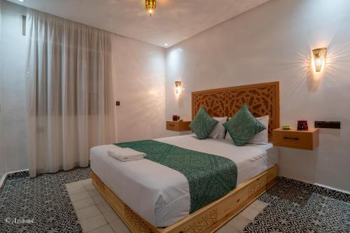 a bedroom with a large bed with green sheets and pillows at Dar jawhara in Chefchaouen