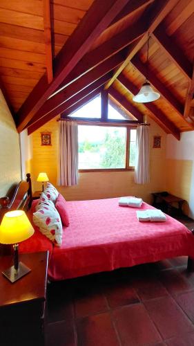 a bedroom with a large red bed with a window at Taiquen Apart Hotel in San Martín de los Andes