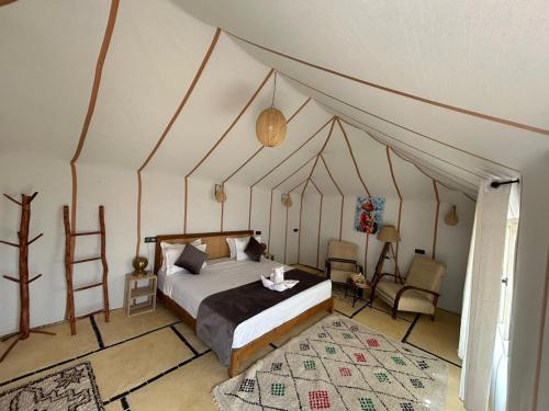 a bedroom with a canopy bed and a chair at Merzouga Dream Camp in Merzouga