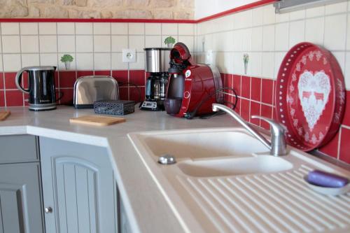 a kitchen sink with a red and white tiled wall at Gîte des forgerons in Sainte-Ouenne