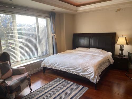 a bedroom with a bed and a chair and a window at Lucky suite, two-bedroom suite with independent entrance in Richmond close to YVR in Richmond