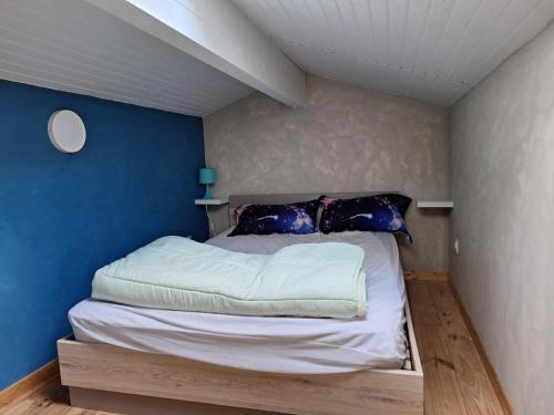 a bed in a room with a blue wall at Petite maison calme in Queyrac