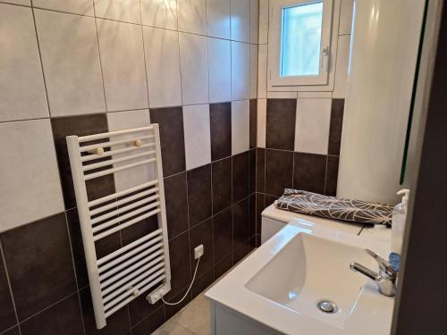 a bathroom with a sink and a toilet and a window at Petite maison calme in Queyrac