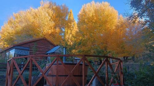 a wooden cabin with a wooden fence and trees at Cabaña Rakin Guilliw in Lonquimay