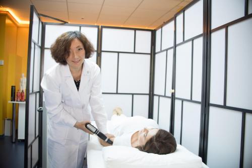 a woman in a white lab coat standing next to a patient at Mirage Medic Hotel in Budapest