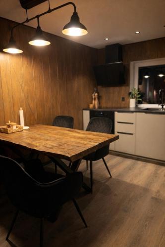 a wooden table in a kitchen with chairs and lights at Slava Spa Relax House in Nakskov