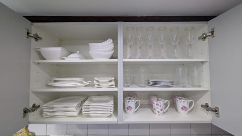 a white cabinet filled with plates and cups and dishes at Lovely Home For You 2 in Biberach an der Riß