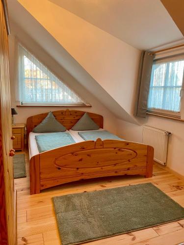 a bedroom with a wooden bed and two windows at Kaiserstube in Quedlinburg