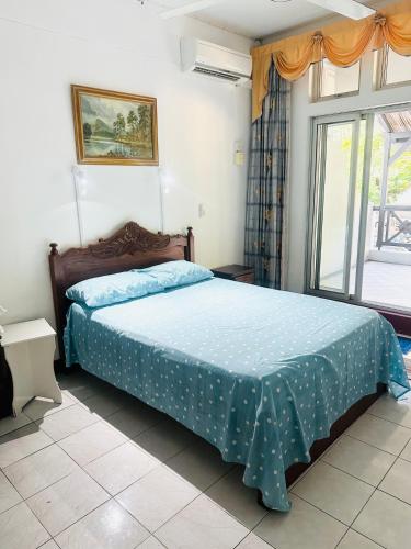a bedroom with a bed with a blue comforter and a window at Pereybere Beach Home in Pereybere