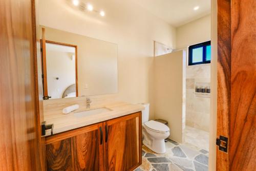 a bathroom with a sink and a toilet and a mirror at Casa Arroyo Pacific in Todos Santos