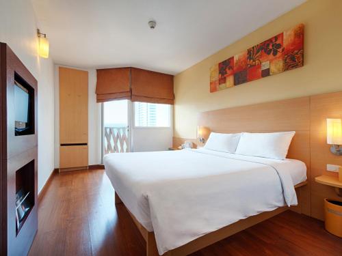 
a hotel room with a bed and a tv at Ibis Pattaya - SHA Extra Plus in Pattaya
