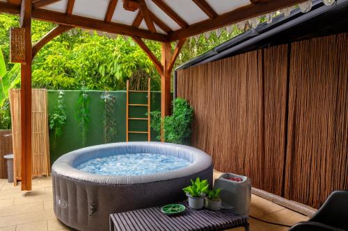 a hot tub in a backyard with a pergola at Appartements Des Roses in Le Lamentin