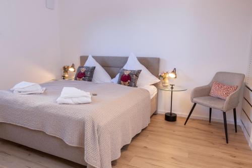 a bedroom with a large bed and a chair at Buhlbach, Black Forest Retreat, mit Sonnenterrasse in Baiersbronn