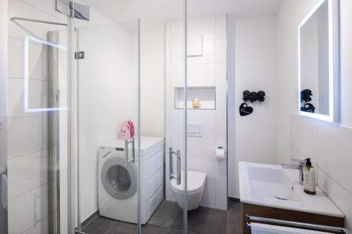 a white bathroom with a washing machine and a toilet at Buhlbach, Black Forest Retreat, mit Sonnenterrasse in Baiersbronn