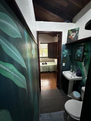 a bathroom with a sink and a toilet and a bed at Mono Azul Cahuita in Cahuita