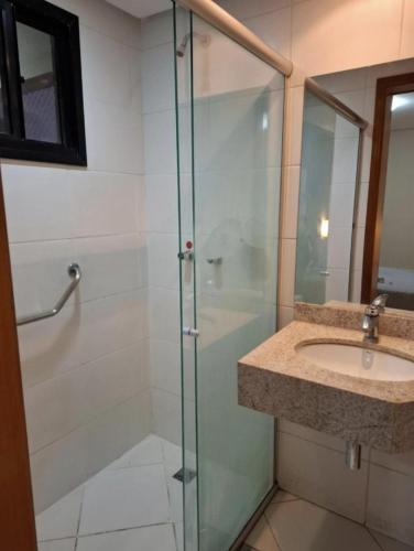 a bathroom with a glass shower and a sink at Crystal Place Flat 509 in Goiânia