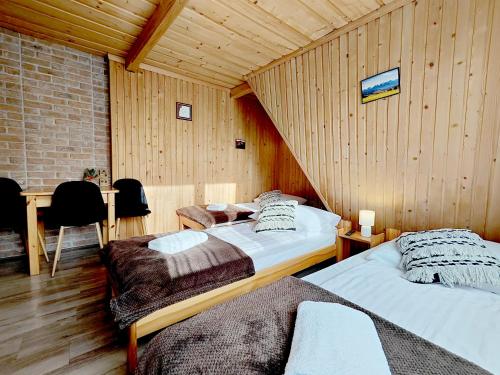 two beds in a room with wooden walls at Noclegi Sarenka in Murzasichle