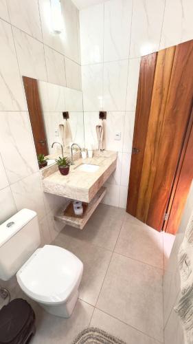 a white bathroom with a toilet and a sink at Milho Ventura II, Vila Pôr do Sol in Sêrro