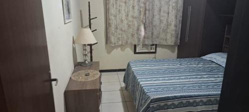 a bedroom with a bed and a table with a lamp at Casa Ampla Vila Muriqui in Vila Muriqui