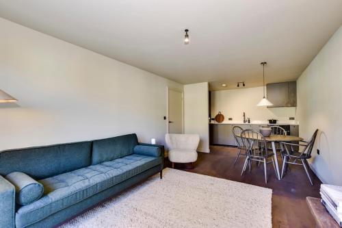 a living room with a blue couch and a table at Luxury 2 bed canal side apartment near Kings Langley station & Warner Brother Studios in Kings Langley