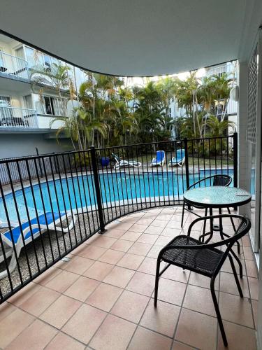 a balcony with a table and chairs and a pool at Beachside Mooloolaba in Mooloolaba