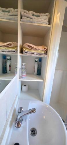 a bathroom with a sink and a shelf with towels at Vanhalla in Heysham