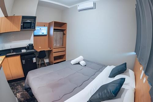 a bedroom with a bed and a desk and a television at Zuccaro Studio in Bauru