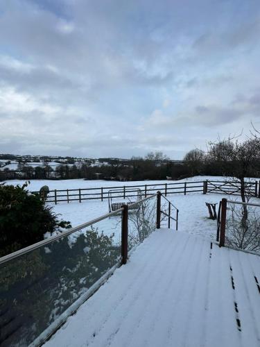 a snow covered field with a fence and a bench at Derbyshire Holiday Cottages in Holmesfield