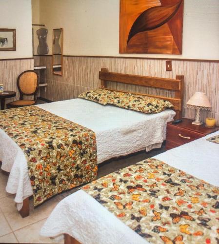 a hotel room with two beds with flowers on them at Pousada do Campo in Ipiabas