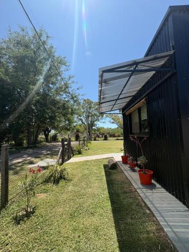 a black house with potted plants in a yard at Los Eucaliptos in Duggan