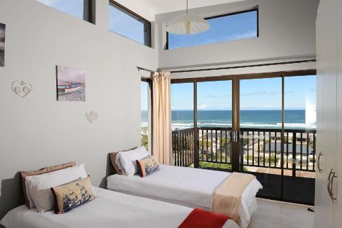 ウィルダネスにあるSea La Vie Beach Houseのベッドルーム1室(ベッド2台付)、海を望むバルコニーが備わります。