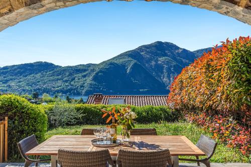 a wooden table and chairs with mountains in the background at Villa Tremezzo in Tremezzo