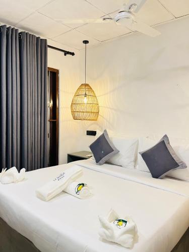 a bedroom with a large white bed with towels on it at La Manga Mirissa in Mirissa