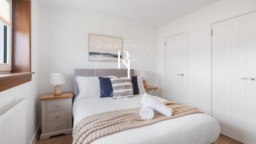 a bedroom with a large white bed with towels on it at The Den at Braehead in Cruden Bay